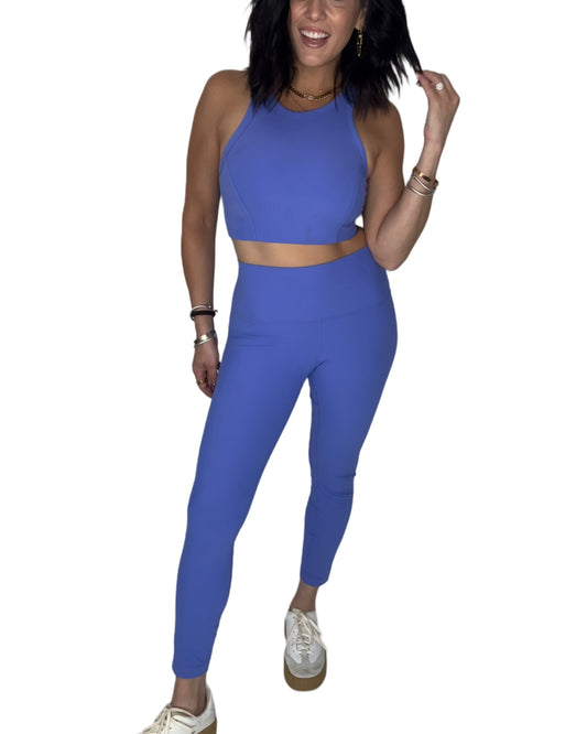 Woman wearing wearing a ribbed blue athletic outfit on a white background