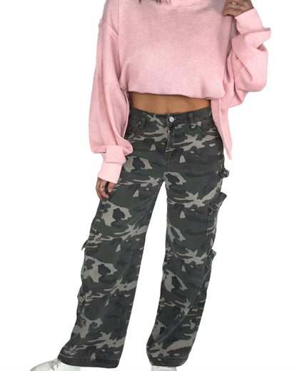 Woman  wearing a pink sweater and camouflage pants on a white background
