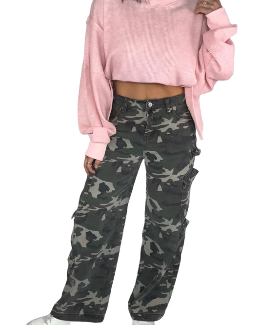 Woman  wearing a pink sweater and camouflage pants on a white background