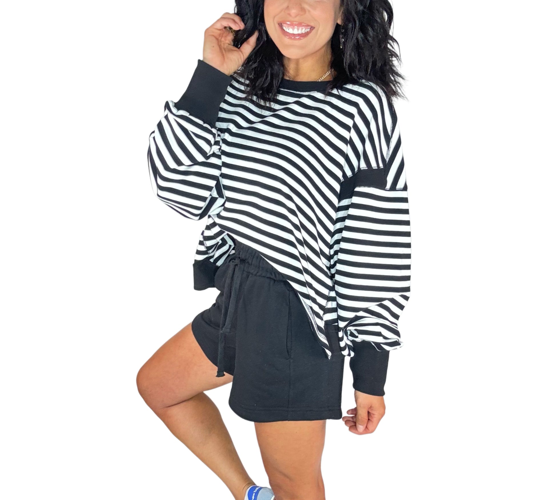 Side profile of a woman wearing black terry shorts with a striped black and white sweatshirt on a white background
