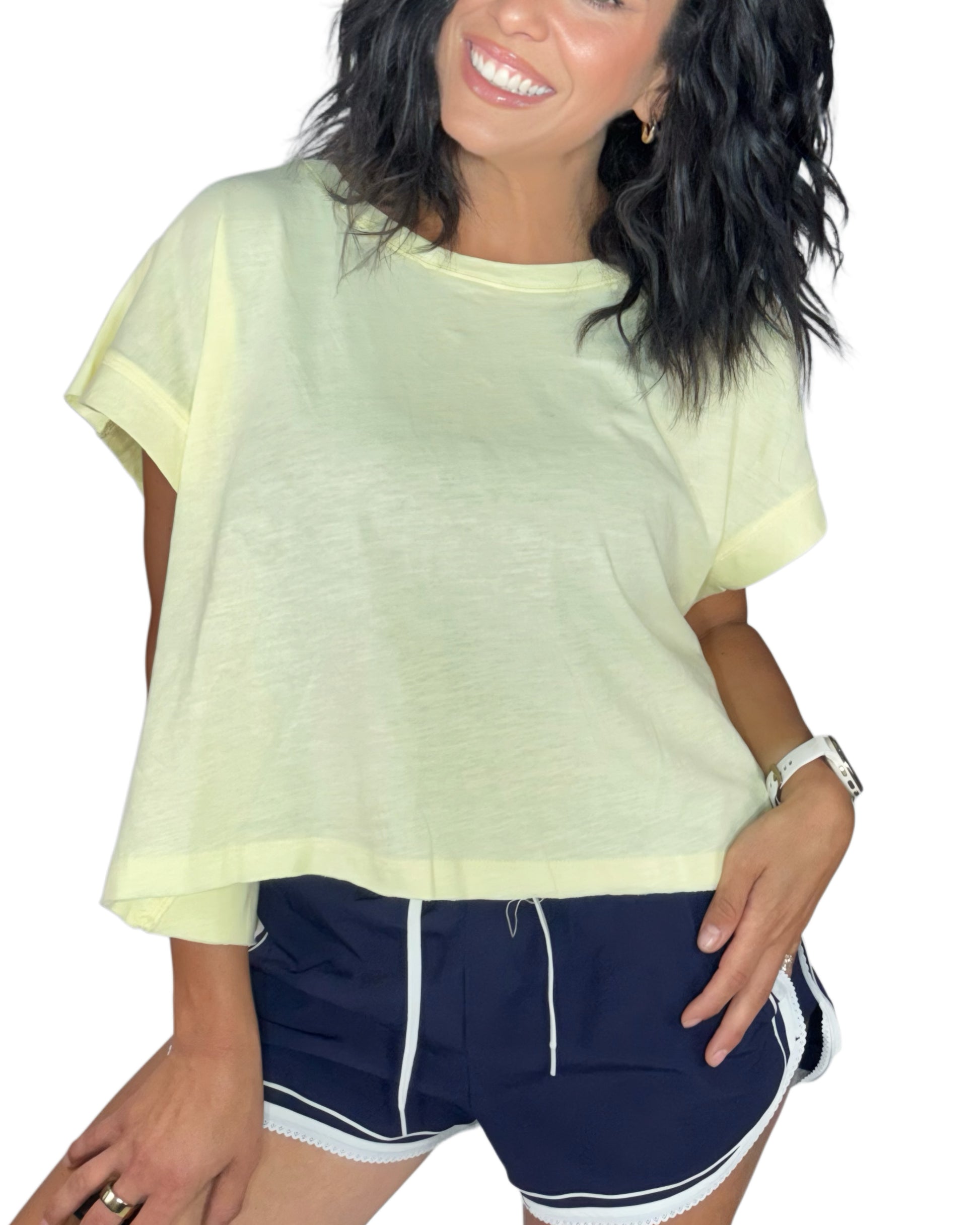 Woman wearing a light yellow top and navy shorts with white trim on a white background