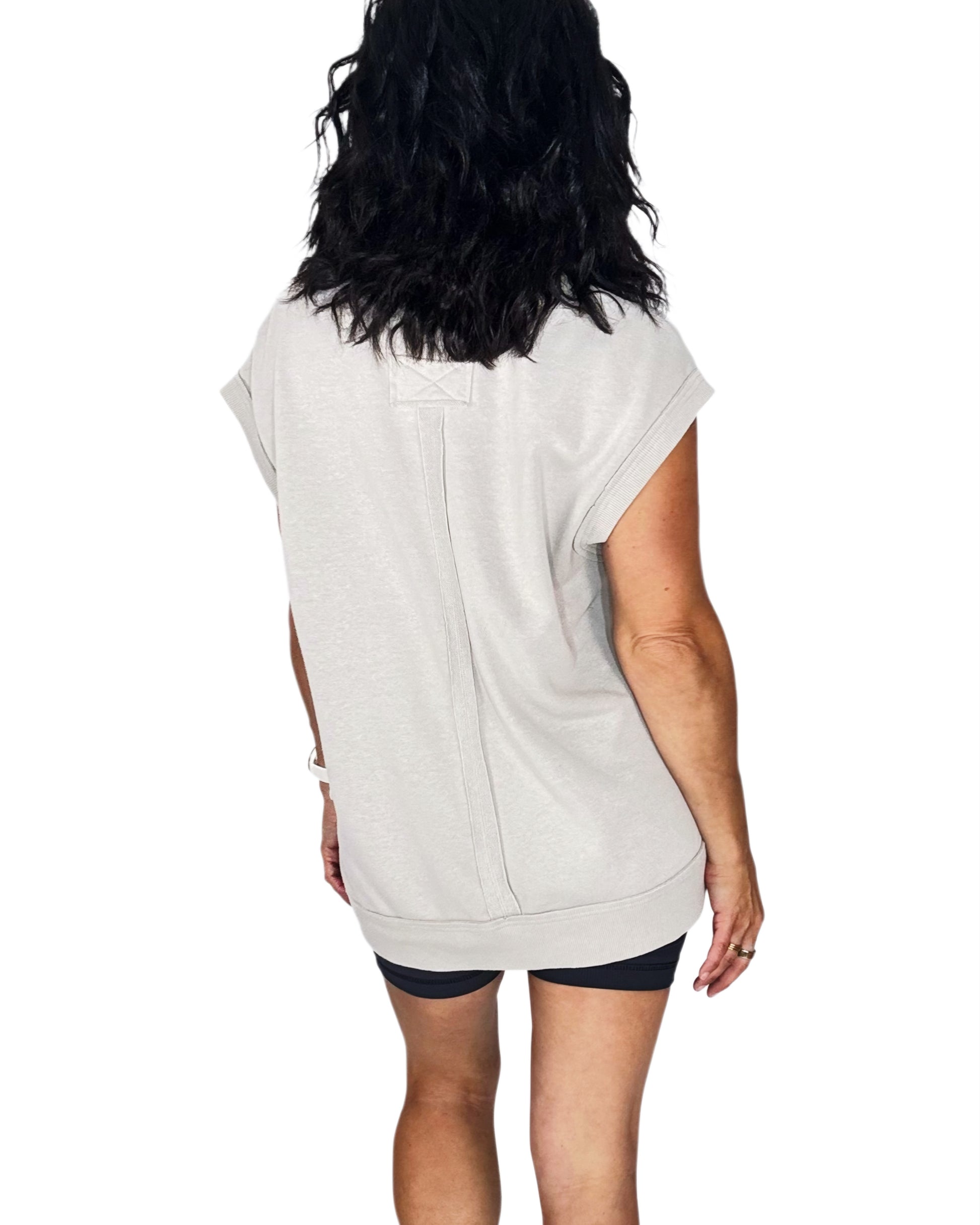 Person wearing a light-colored sleeveless top on a white background