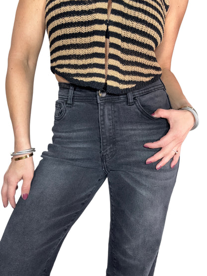 Person wearing a striped sleeveless top and dark jeans on a white background