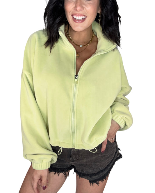 Woman wearing a light green fleece jacket on a white background