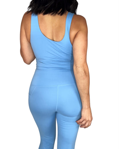 Back profile of a woman wearing a powder blue tank top and leggings set on a white background 