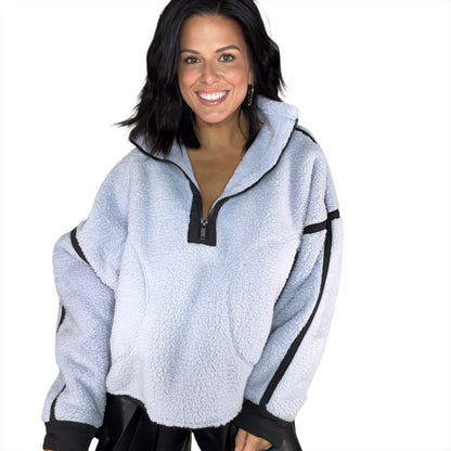 Woman wearing a light blue fleece pullover with black accents on a white background