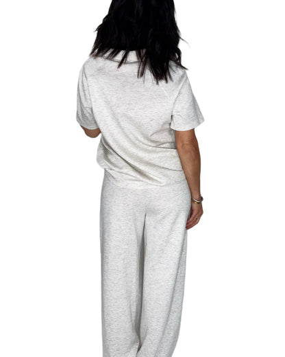 Back profile of a woman wearing a light gray  lounge outfit with a white background