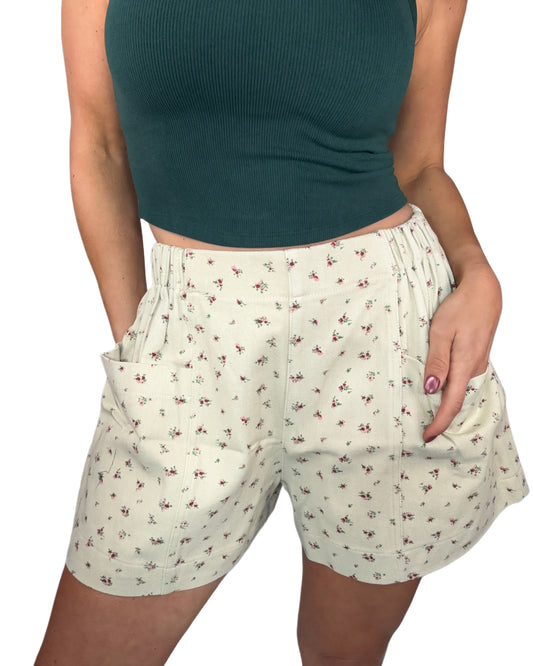 Woman wearing floral shorts and a green top on a white background