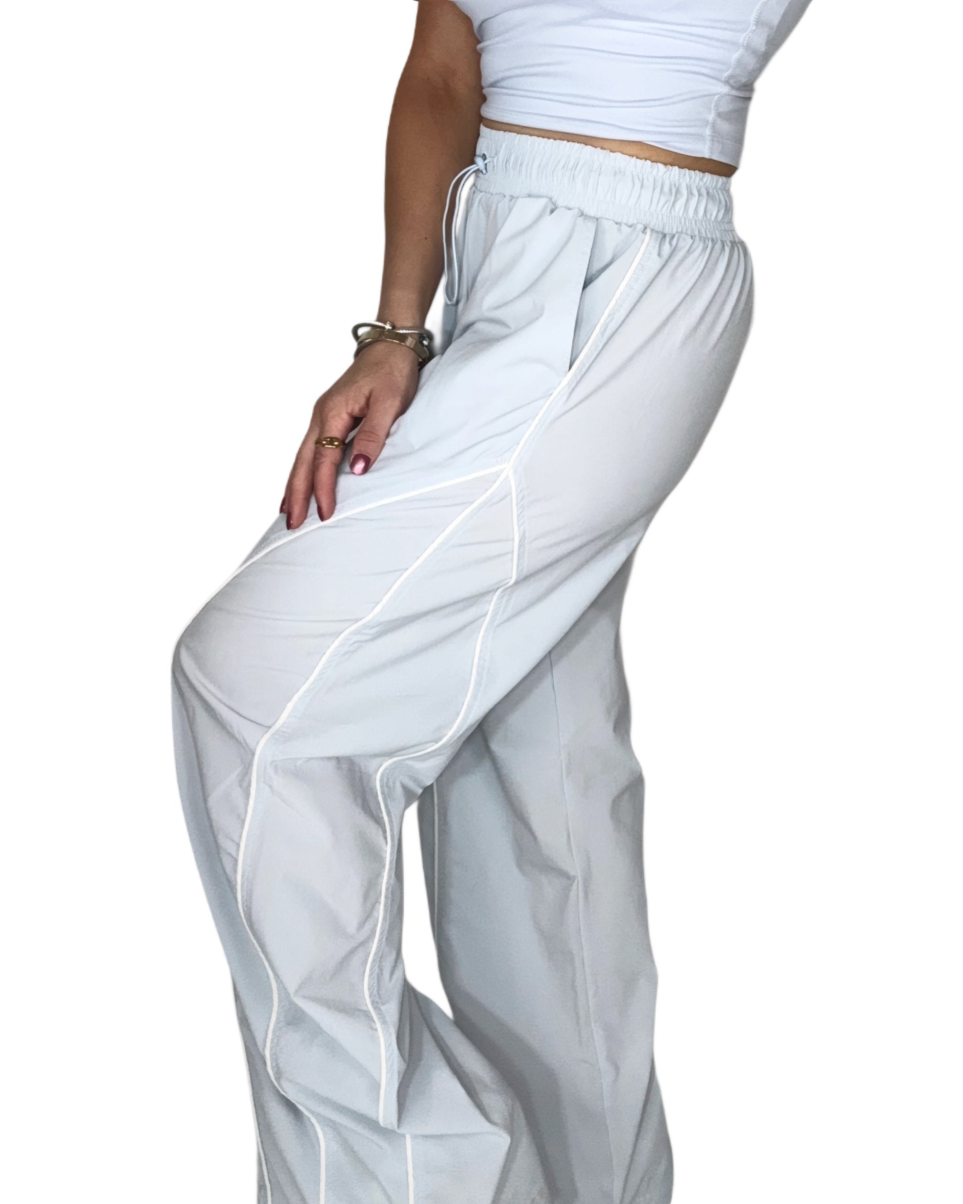Side profile of a woman wearing light blue track pants with matching tank, on a white background