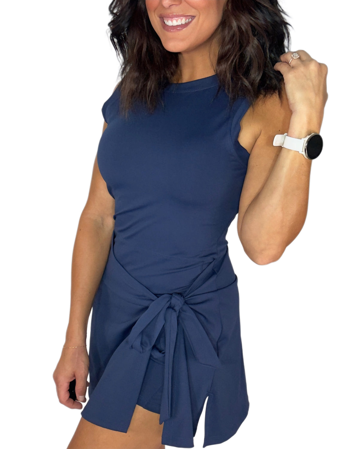 Side profile of a woman modeling a sleeveless navy mini active romper  with a side-tie detail, set against a plain white background.
