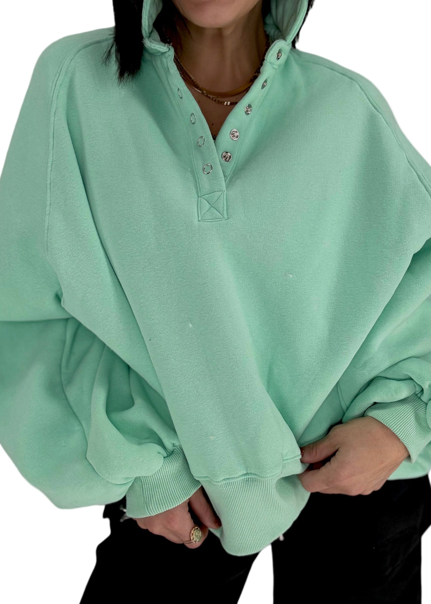 Woman wearing a light green sweatshirt with a plain background