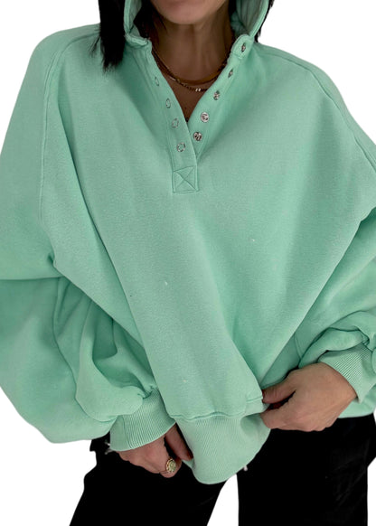 Woman wearing a light green sweatshirt with a plain background