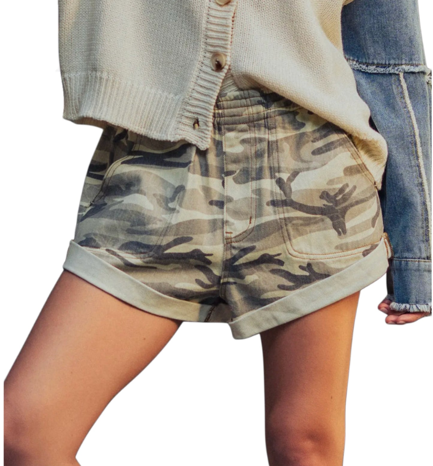 Woman wearing camo shorts and a cream sweater on a white background 