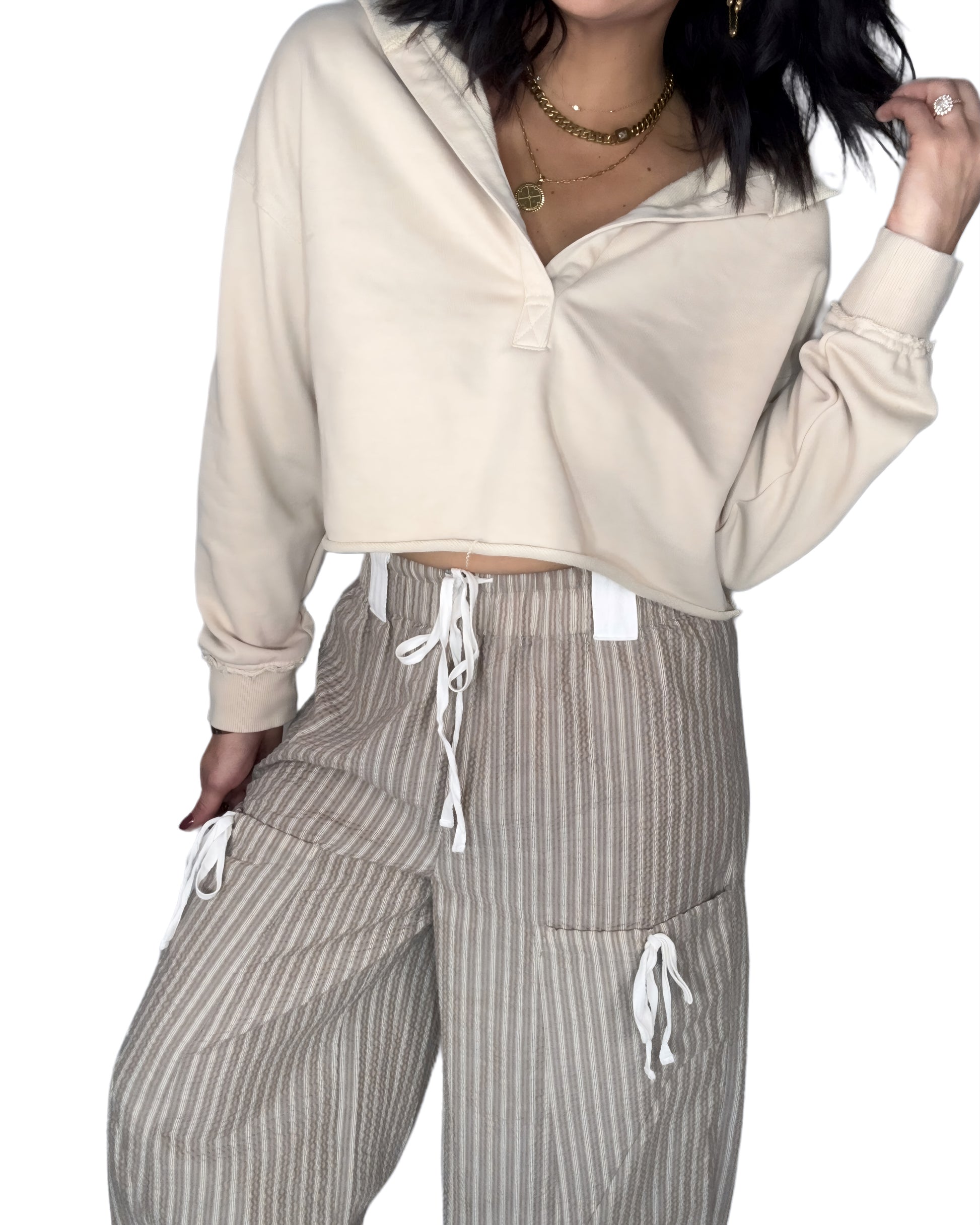 Woman wearing a tan hooded top and striped pants on a white background