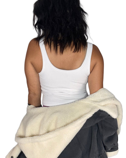 Back profile of a woman wearing a ribbed active tank top with a sherpa jacket hanging off her shoulders, lilac bottoms, on a white background 