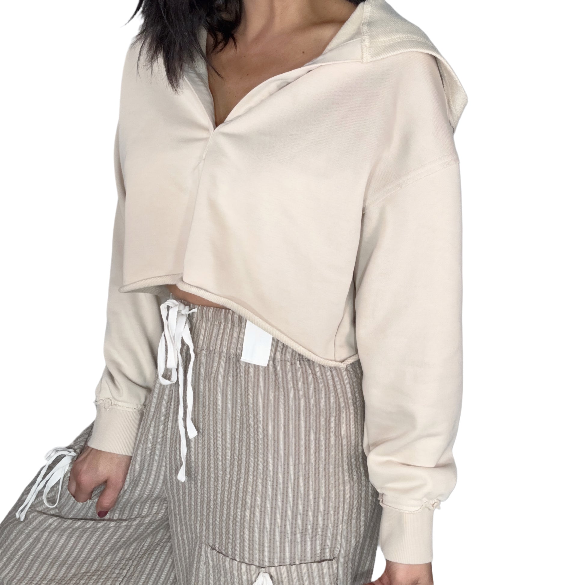 Side profile of a woman wearing a tan hooded top and striped pants on a white background