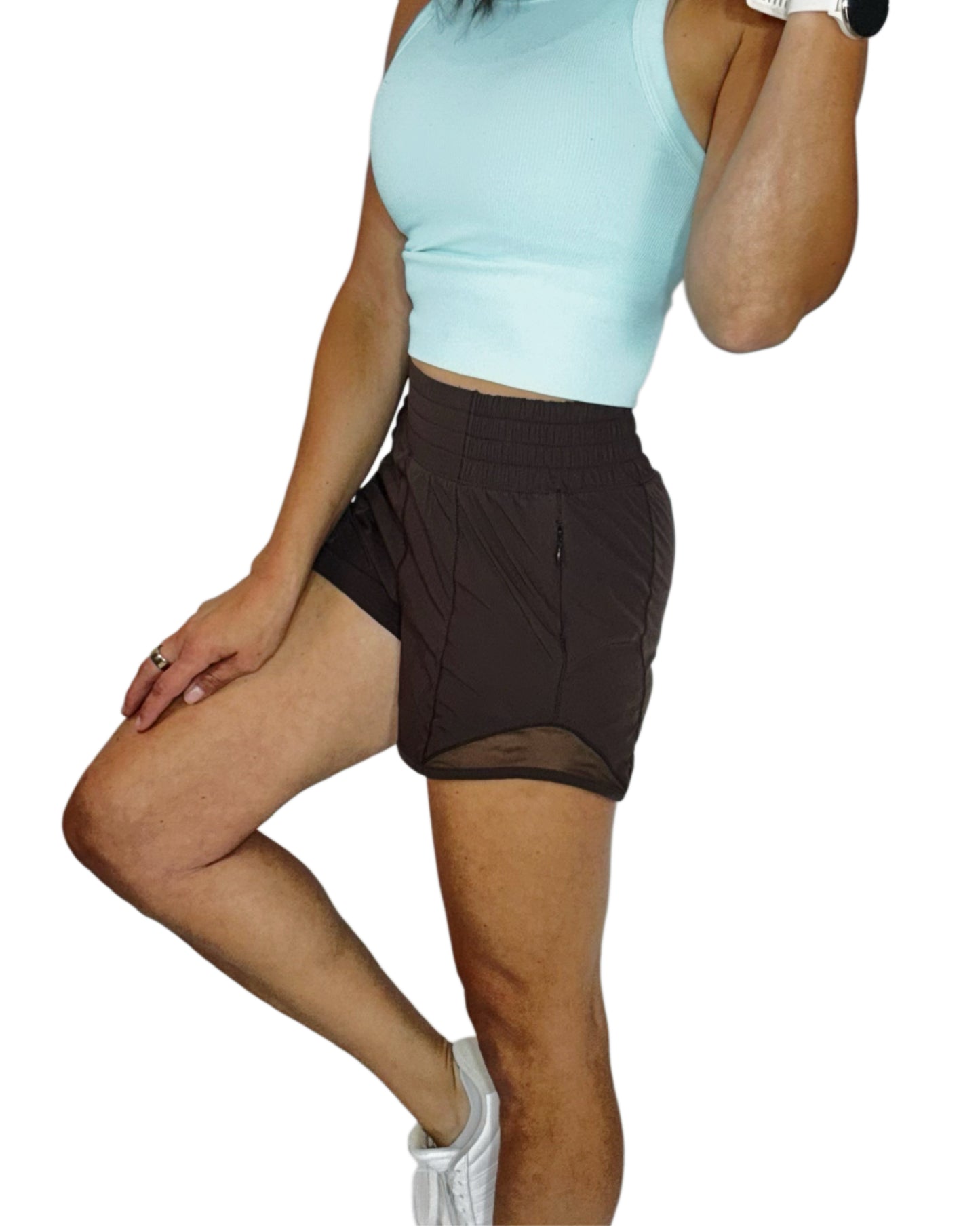 Side profile of a woman wearing brown active shorts with a blue ribbed tank, on a white background 