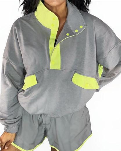 Close  up of a woman wearing a stone taupe short set with lime accents on a white background