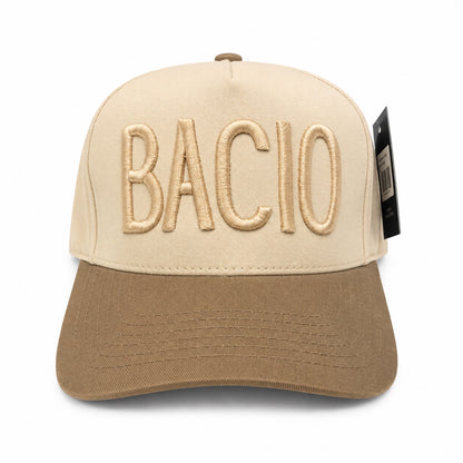 Tan hat with dark tan bill and the word Bacio across the front on a white background