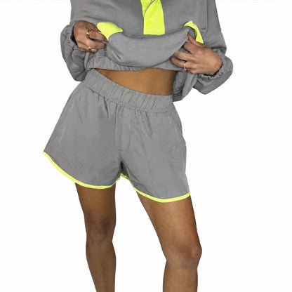 Close up of a woman wearing  stone taupe short with lime accents with a matching pull over, on a white background