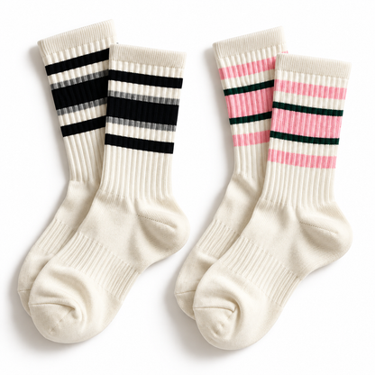 Two pairs of off-white ribbed crew socks with three black horizontal stripes near the cuff and the other with pink horizontal stripes near the cuff on a white background 