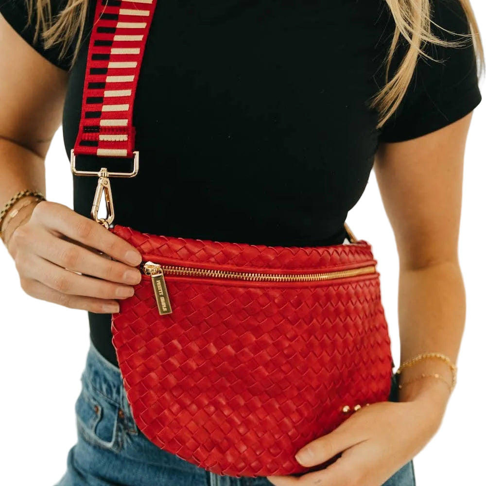 Person holding a red woven handbag with a striped strap against a neutral background